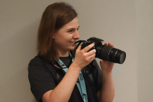 A student holding a camera and smiling