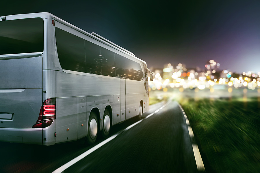 A charter bus driving down the road, approaching a city in the distance