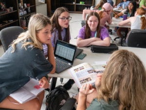 students collaborating around a table discussing yearbook layouts and planning for the year