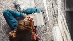 overhead shot of a teen girl writing in a notebook